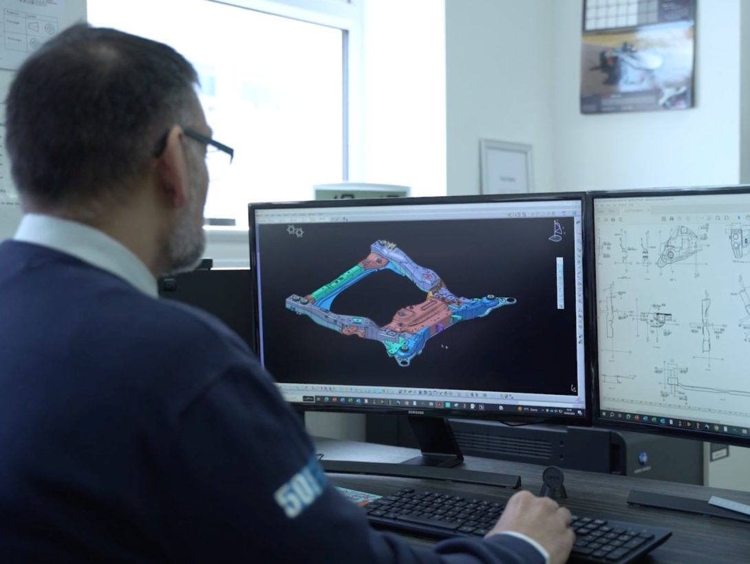 Engineer reviewing CAD model and technical drawings on dual monitors